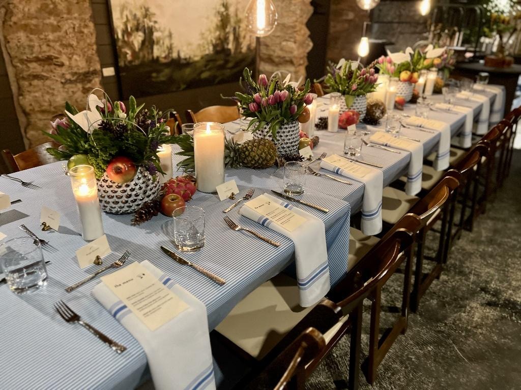 Elegantly set long table in The Saluda Inn Wine Cellar with floral centerpieces and candles for a corporate dinner
