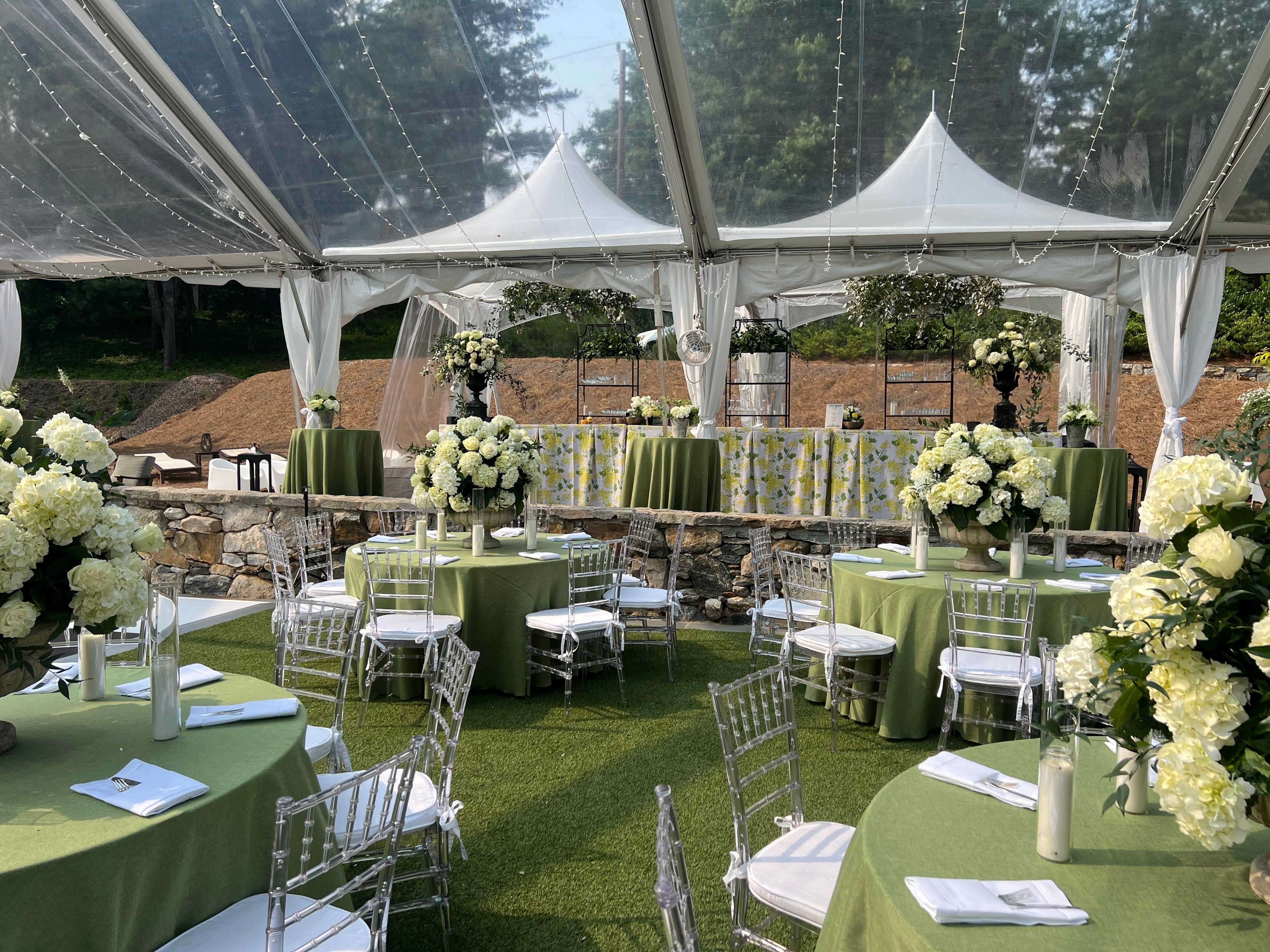 Wedding guests at cocktail hour under yellow-lit tent at The Saluda Inn wedding venue