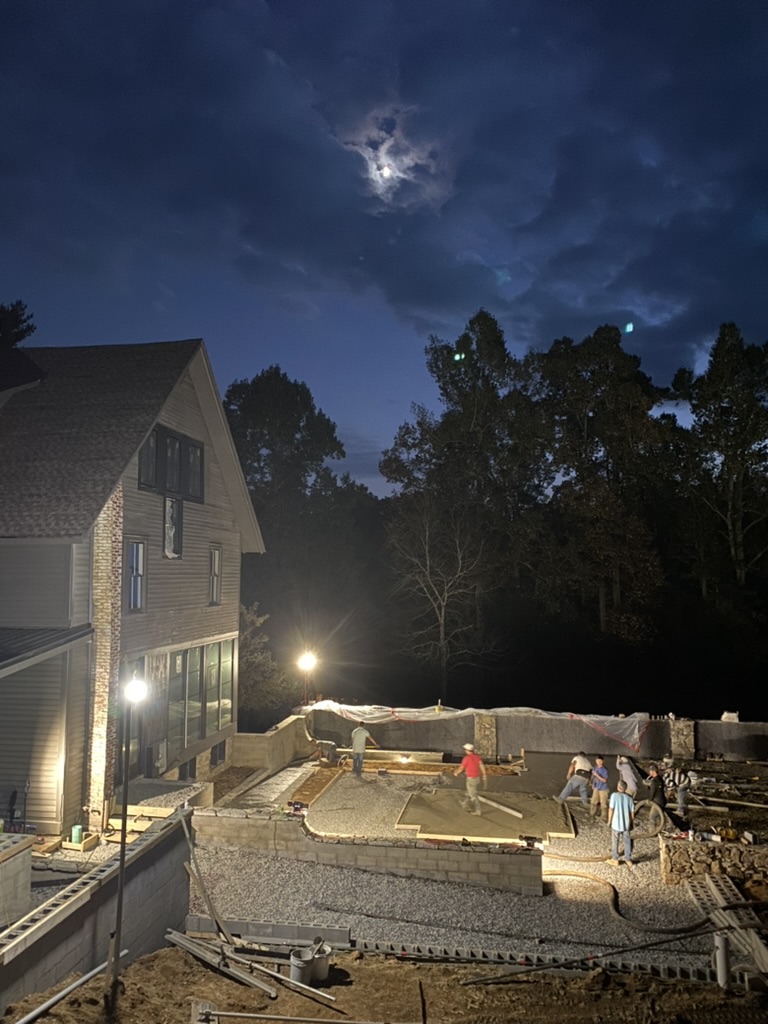 Moonlit pour — crew finishing the terrace slab under a full moon