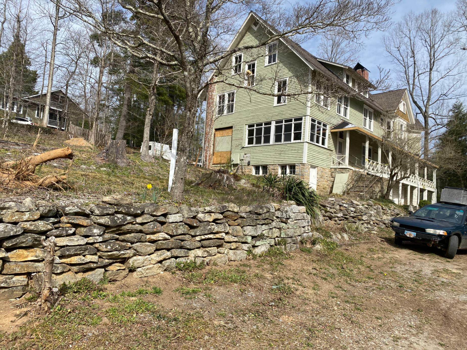 Exterior early renovation — stone retaining wall & original siding