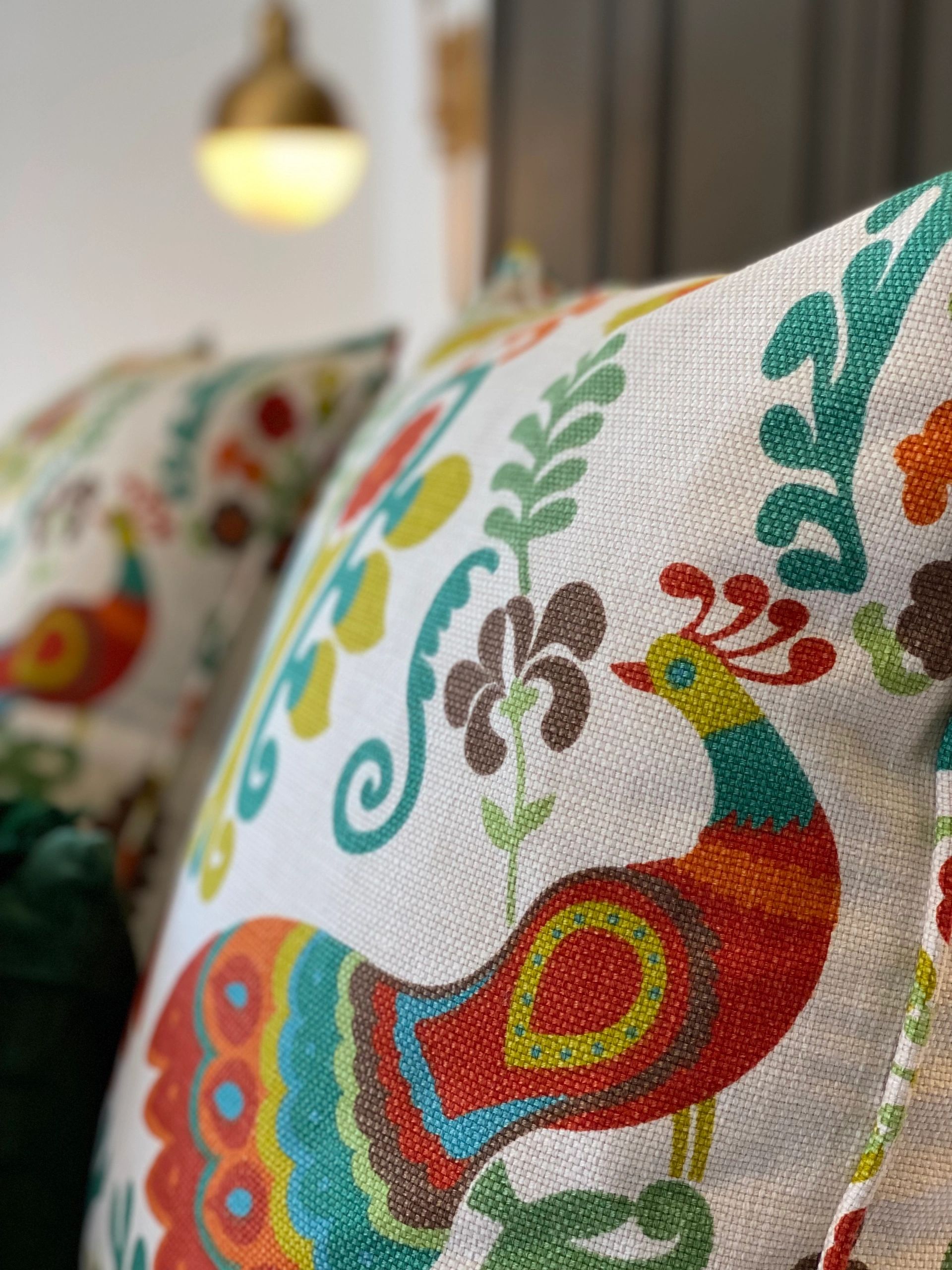 Colorful peacock design on a decorative pillow with floral patterns